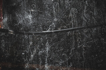 Abstract black grunge textured background with white scratches, stains, and dust effects. The rough, worn surface creates a dramatic, dark, and artistic impression. © Hendri