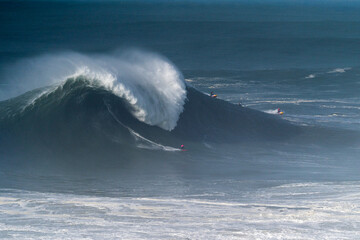 Surfer riding a big wave at Nazar&eacute;, Portugal, captured at the iconic Praia do Norte. Powerful Atlantic Ocean surf, extreme conditions, and world-class big wave surfing.