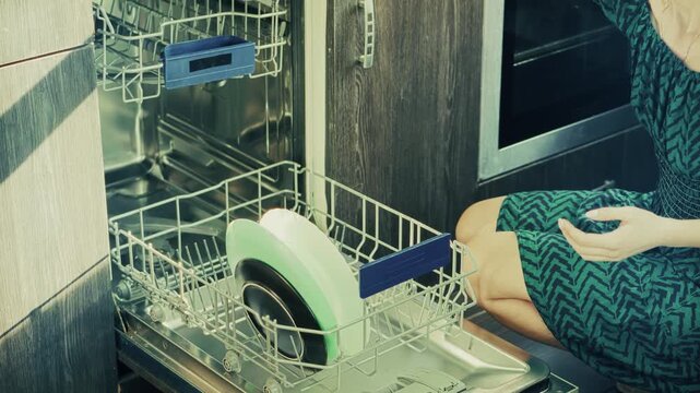 Woman Loading Dirty Plates Into Dishwasher. Home Appliance Usage For Cleaning