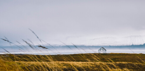 Lonely house in Norwegian fjord with snowy mountains in the background