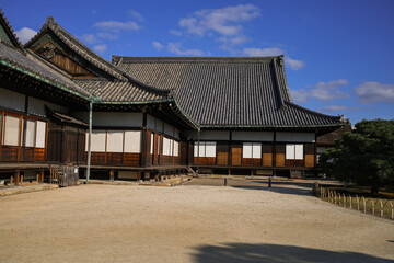 Kyoto,Nijo. Historic Japanese Temple Gate With Visitors In Courtyard Under A Bright Blue Sky