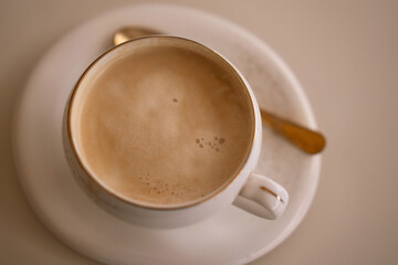 Coffee cappuccino elegant overhead view of creamy latte in white porcelain cup with golden spoon