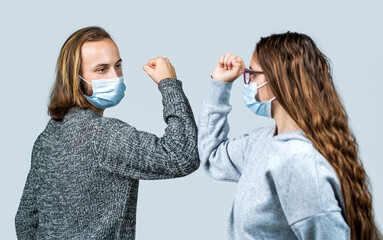 Couple of friends greets with elbow bumping in the coronavirus pandemic new normal. Handshake in quarantine new normal time. Elbows bump. Two people bump elbows. Friends in safety mask