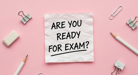 A blank sheet of paper with ARE YOU READY FOR EXAM? written on it sits on a pink surface with stationery.