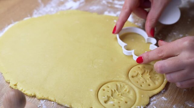 Detailed view of hands using a cookie cutter on rolled dough. The scene captures the precision and artistry of biscuit making, set in a cozy kitchen environment.