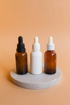 Different serum cosmetic bottles, white and dark brown dropper bottle container and packaging skincare product. studio pastel light background.