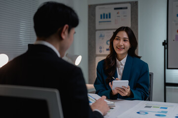 Asian businesswoman discussing finance with male colleague in office