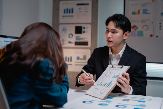 Asian business executive presenting data to stressed colleague - Powered by Adobe