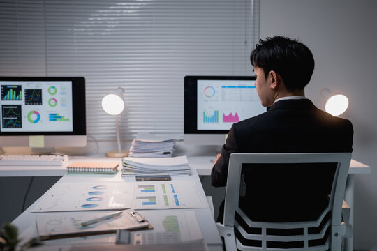 Businessman analyzing financial data on computer at night - Powered by Adobe