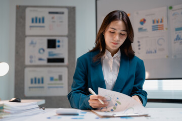 Asian businesswoman analyzing financial data and charts in office