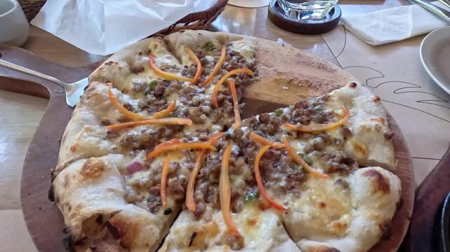 Handheld dolly forward from lunch spread to a serving of sisig pizza at a restaurant that shows fusion cuisine of Italian and Filipino food
