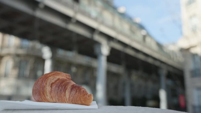 Croissant in Foreground with Train Passing on Bridge in Paris France
