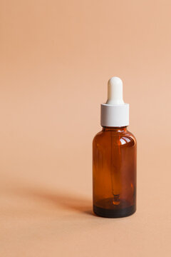 Different serum cosmetic bottles, white and dark brown dropper bottle container and packaging skincare product. studio pastel light background.