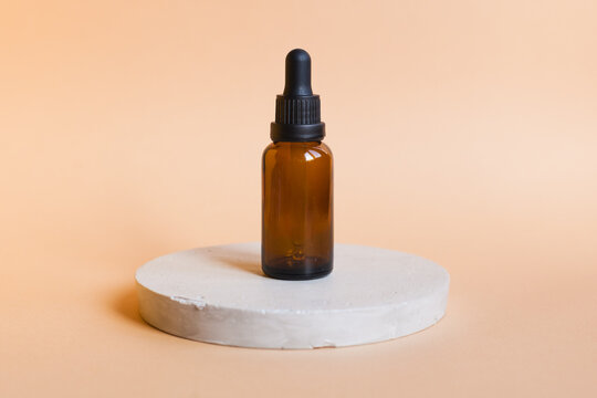 Different serum cosmetic bottles, white and dark brown dropper bottle container and packaging skincare product. studio pastel light background.