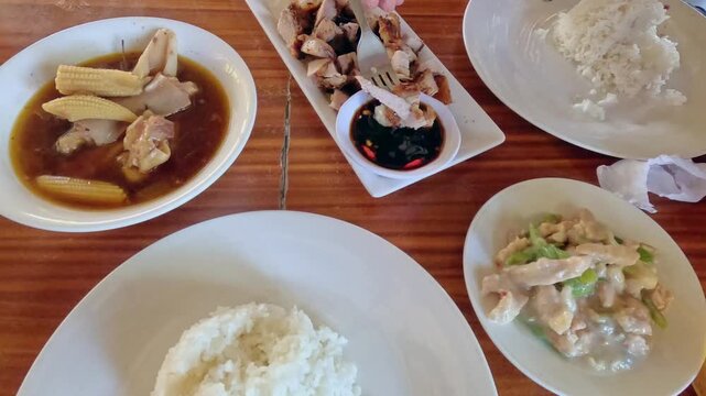 Overhead view dipping lechon kawali in soy sauce served with balbacua, halang halang and rice, authentic traditional local Filipino food