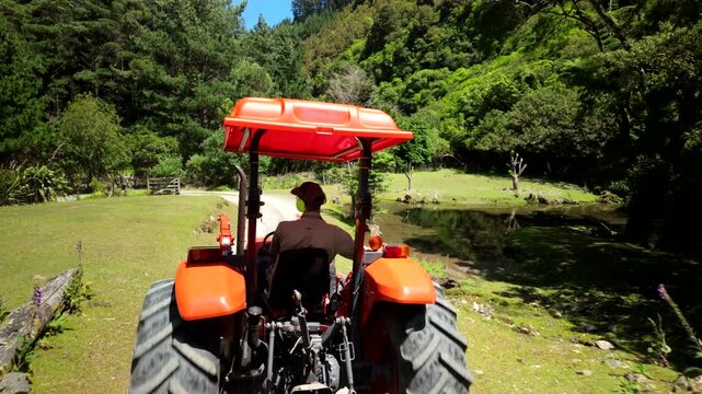 Tractor driving past pond on forest farm road