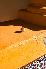 Outdoor scene with vibrant yellow surface with colorful ball for product presentation, social media post or header for website. Template background for text.