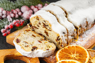 Traditional Christmas stollen, sweet fruit loaf sliced on wooden board, dusted with powdered sugar...
