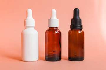 Different serum cosmetic bottles, white and dark brown dropper bottle container and packaging skincare product. studio pastel light background.