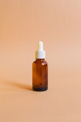 Different serum cosmetic bottles, white and dark brown dropper bottle container and packaging skincare product. studio pastel light background.