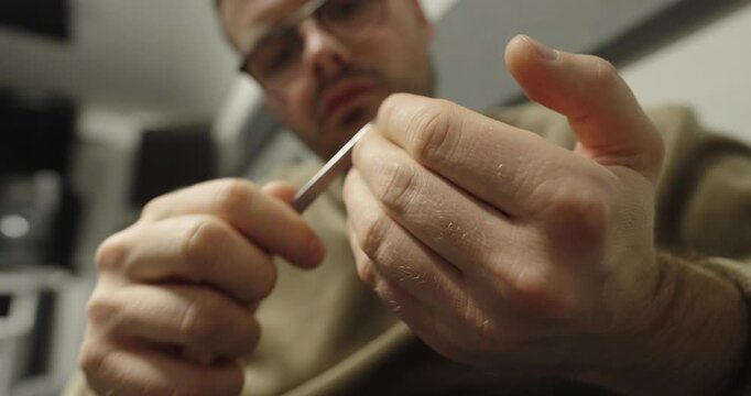 A man carefully files his nails in a close-up grooming moment.
