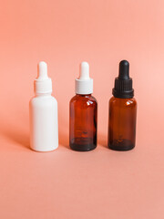 Different serum cosmetic bottles, white and dark brown dropper bottle container and packaging skincare product. studio pastel light background.