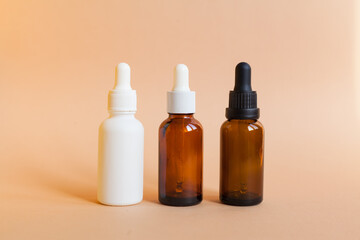 Different serum cosmetic bottles, white and dark brown dropper bottle container and packaging skincare product. studio pastel light background.