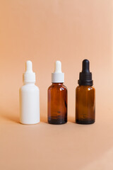 Different serum cosmetic bottles, white and dark brown dropper bottle container and packaging skincare product. studio pastel light background.