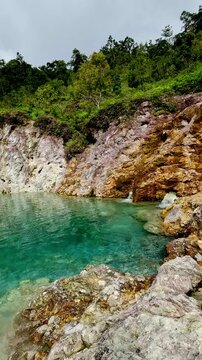 Stunning scenery of the JABA sulfur lagoon featuring the clear blue waters, lime cliffs and dense green forest foliage in Amlan, Negros Oriental, Philippines