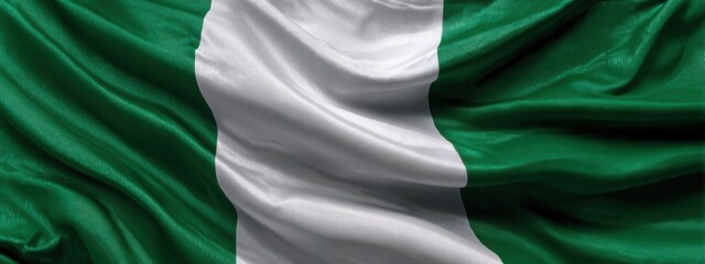 Obraz premium Nigerian flag waving in the wind during daylight in a public space showing national pride and identity
