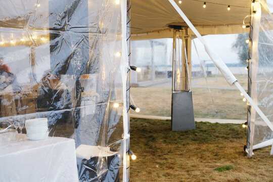 Tent interior decorated with a vibrant garland, illuminated by string lights, creating a festive atmosphere for gatherings and celebrations, perfect for outdoor events and parties