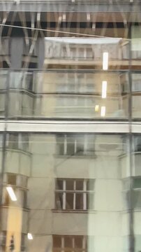 Cityscape with detailed architecture, Elaborate building facades reflected in bustling city view, Intricate architectural details from moving vehicle Vertical shot taken on mobile devicr.