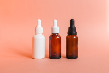 Different serum cosmetic bottles, white and dark brown dropper bottle container and packaging skincare product. studio pastel light background.
