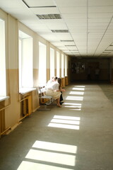 Teacher engages with upset student in bright school hallway, sunlight streaming through windows, creating a warm and supportive atmosphere for emotional discussion
