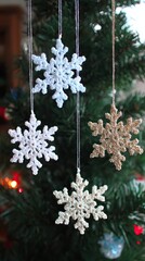 three white crocheted snowflakes and one gold star ornament hanging on the christmas tree