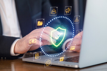 Professional working on laptop with security icons displayed on screen during a business project