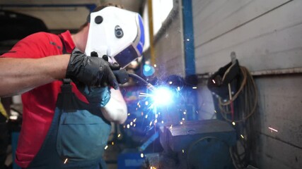 Skilled mechanic in protective gear welding metal piece in workshop, showcasing sparks flying, tools nearby, and the dynamic process of metalwork in an automotive service environment - Powered by Adobe