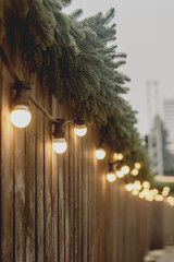 Warm String Lights on Wooden Fence with Evergreen Decor