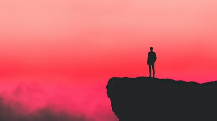 Silhouette of Man Standing on Edge of Cliff Against Dramatic Pink Sky at Sunset