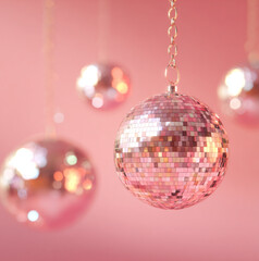 Obraz premium A dreamy pastel disco scene a disco ball hanging from the ceiling, bathed in soft pink and blush lighting. Shallow depth of field with one disco ball in sharp focus, and a solid pink background