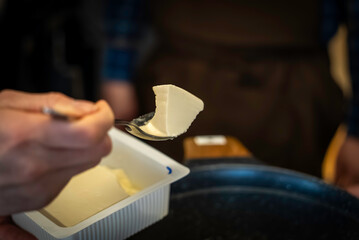 豆腐をすくって入れる風景