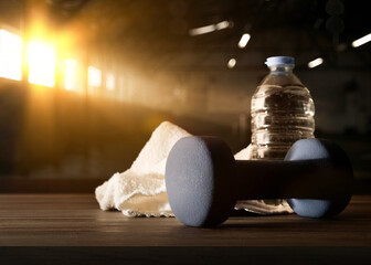 Sport training with dumbbell on wooden bench and gym background