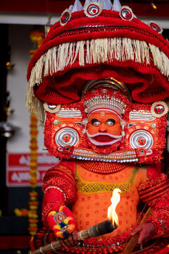 Kannur, Kerala / India &ndash; December 12, 2025:
A Theyyam performer dressed in traditional red ritual costume holds a flaming torch during a Theyyam ritual performance at a temple in Kannur district