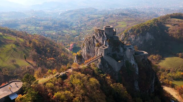 Aerial drone view of Srebrenik Fortress, a medieval stronghold perched dramatically atop a steep rock cliff in Bosnia and Herzegovina