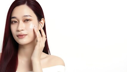 Fototapeta premium A beautiful young Asian woman applying skincare product to her radiant face.