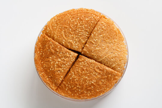 An overhead view of crispy, golden-brown Kue Semprong or Love Letter cookies, a thin, folded Southeast Asian snack. Arranged inside its clear plastic storage container.