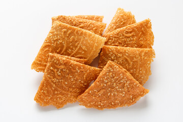 Top view of crispy, golden-brown Kue Semprong or Love Letter cookies, a thin, folded Southeast Asian snack. Isolated on a white background.