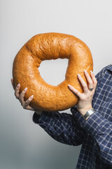 Woman holding giant bagel against grey background