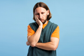 Unhappy man feeling bored, tired, or pensive, hand supporting his cheek