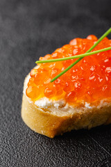 Single canape with red caviar and chives garnish